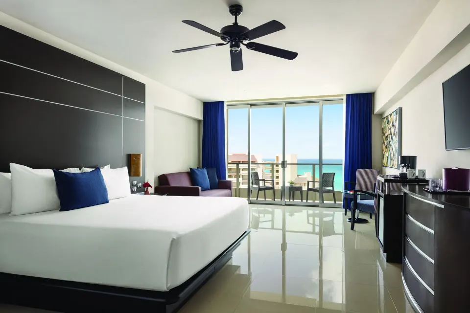 Standard Suite with king bed and ocean-facing balcony at Seadust Cancún Family Resort.