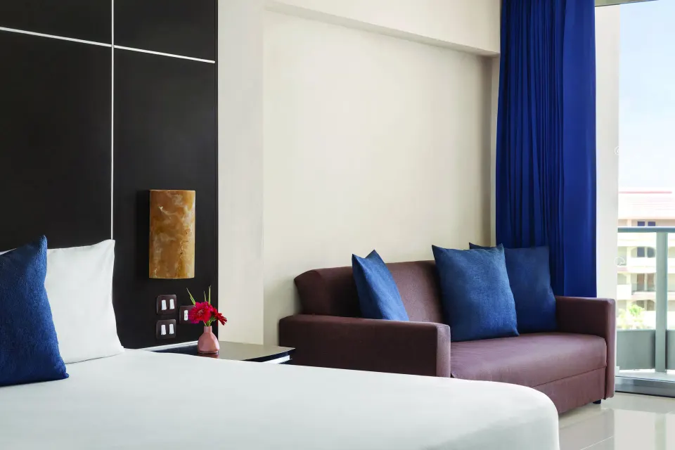 Standard Suite bed and sofa seating area at Seadust Cancún Family Resort.