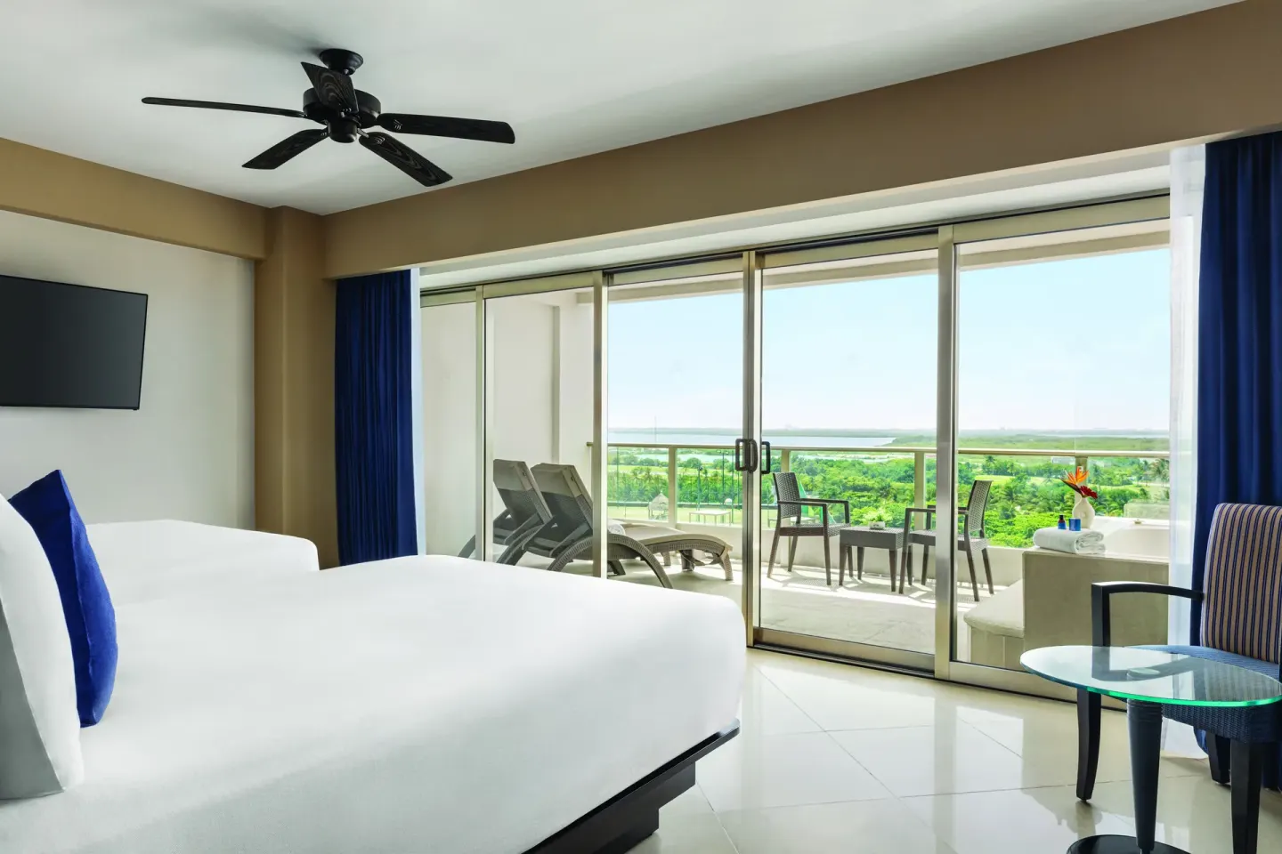 Standard Suite king bed and large terrace doors at Seadust Cancún Family Resort.