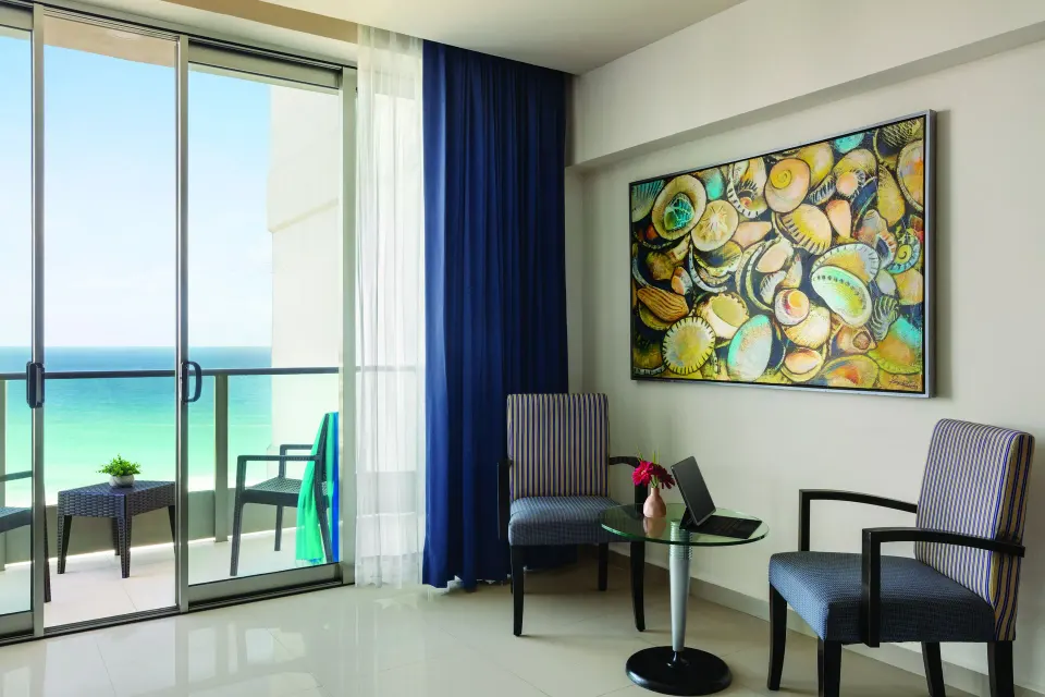 Standard Suite sitting area and balcony ocean view at Seadust Cancún Family Resort.
