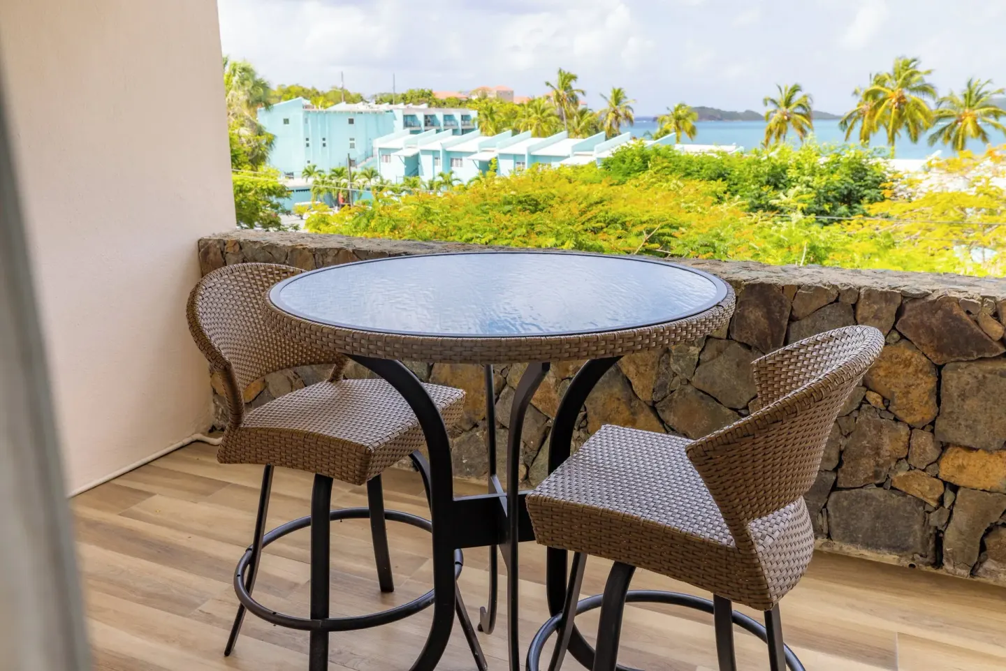 Covered balcony with two woven chairs and a water view at Secret Harbour Beach Resort.