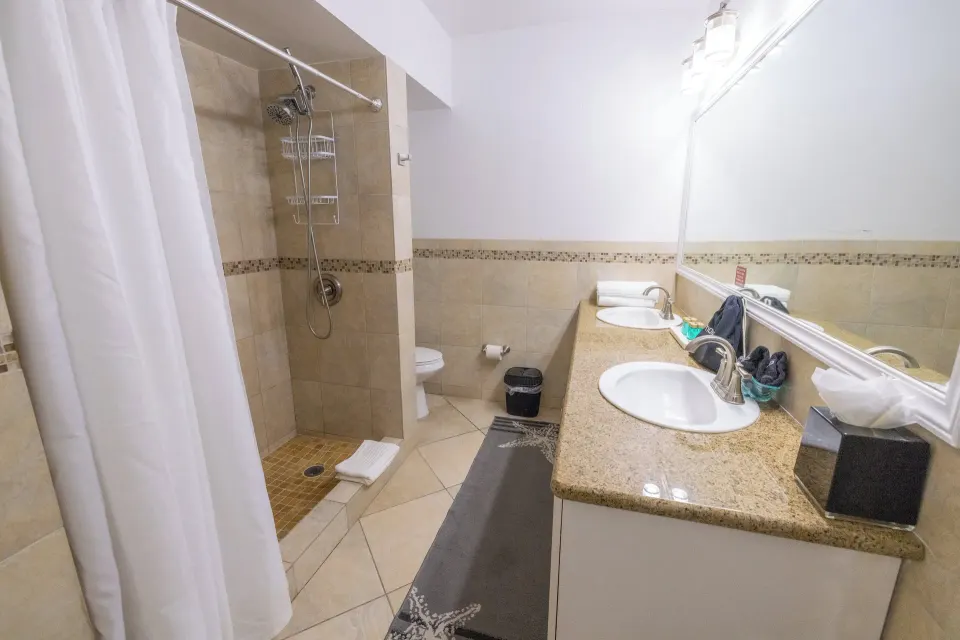 Guest bathroom with double sinks and tiled walk-in shower at Secret Harbour Beach Resort.