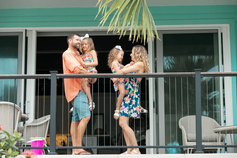 Family standing on a guest room balcony at Secret Harbour Beach Resort.