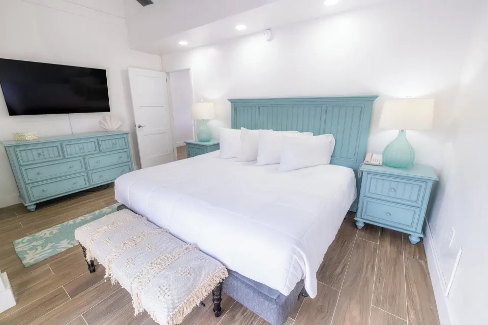 White king bed with turquoise furniture in a guest room at Secret Harbour Beach Resort.