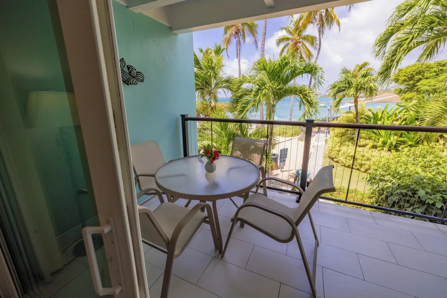 Private balcony with table, chairs, palms, and bay view at Secret Harbour Beach Resort.