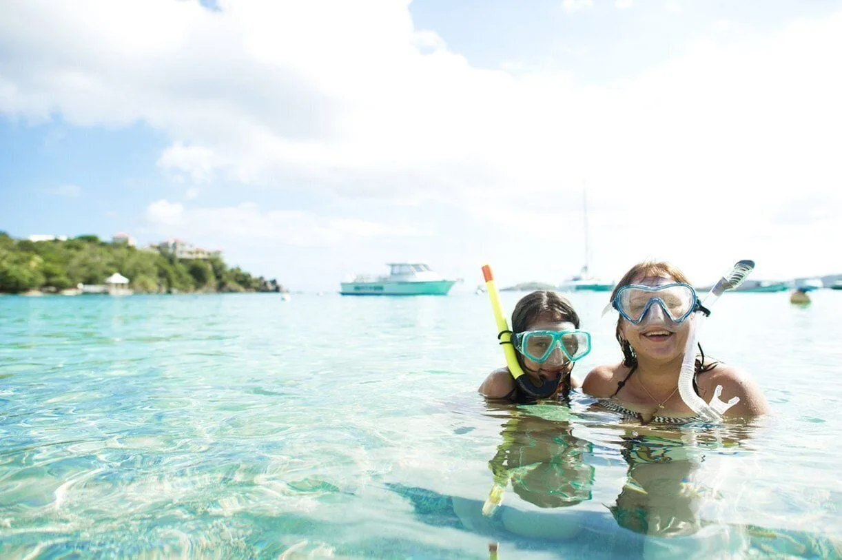 Two snorkelers smile in clear bay water at Secret Harbour Beach Resort.