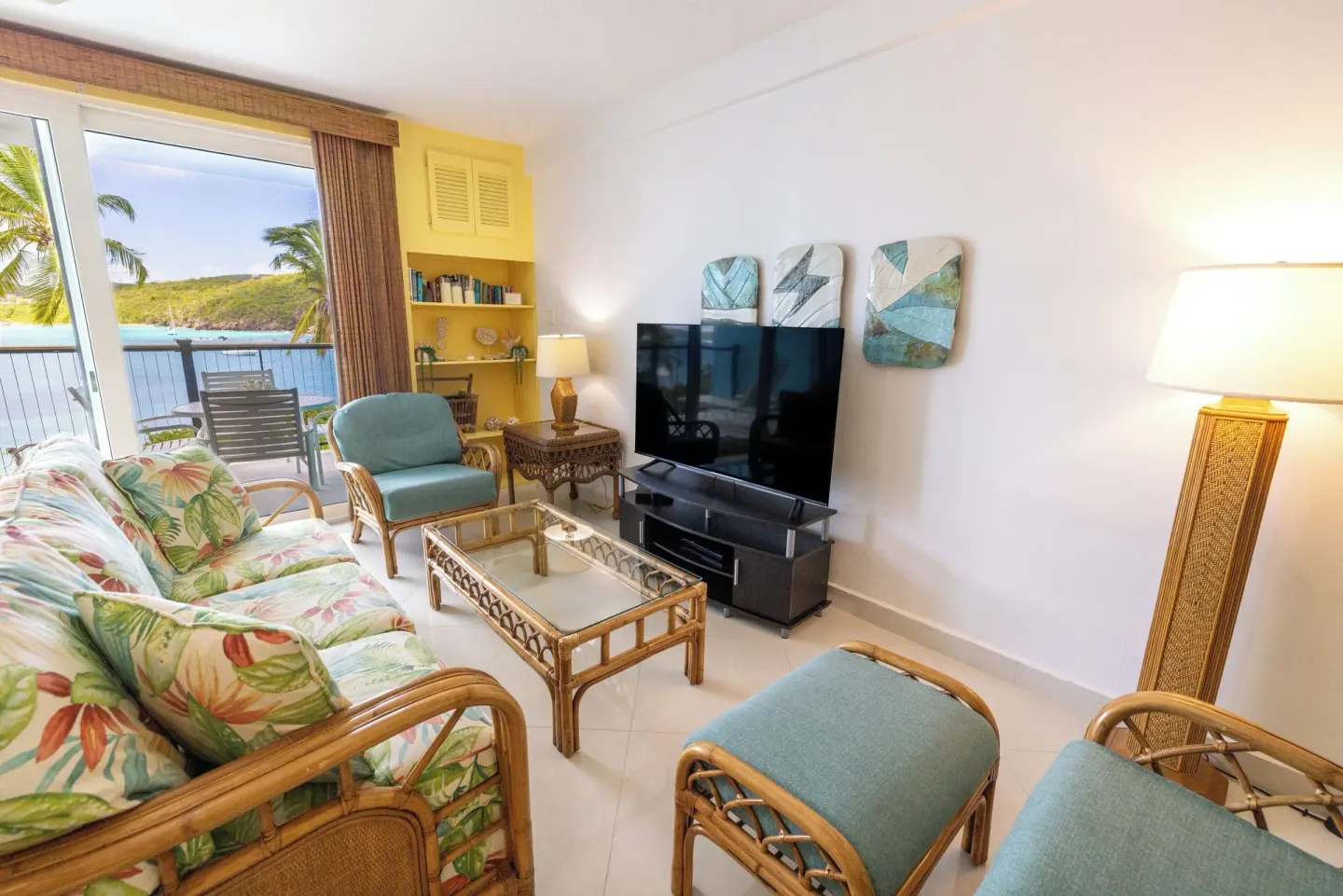 Suite living room at Secret Harbour Beach Resort with sofa, TV, and balcony by the water.