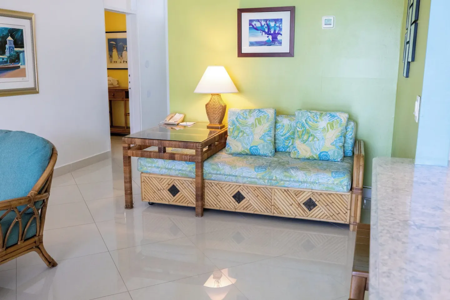 Rattan loveseat seating area in a suite at Secret Harbour Beach Resort with pale green wall.