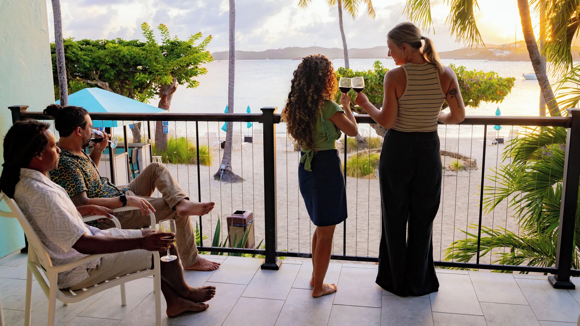 Guests drinking wine on a sunset balcony at Secret Harbour Beach Resort.