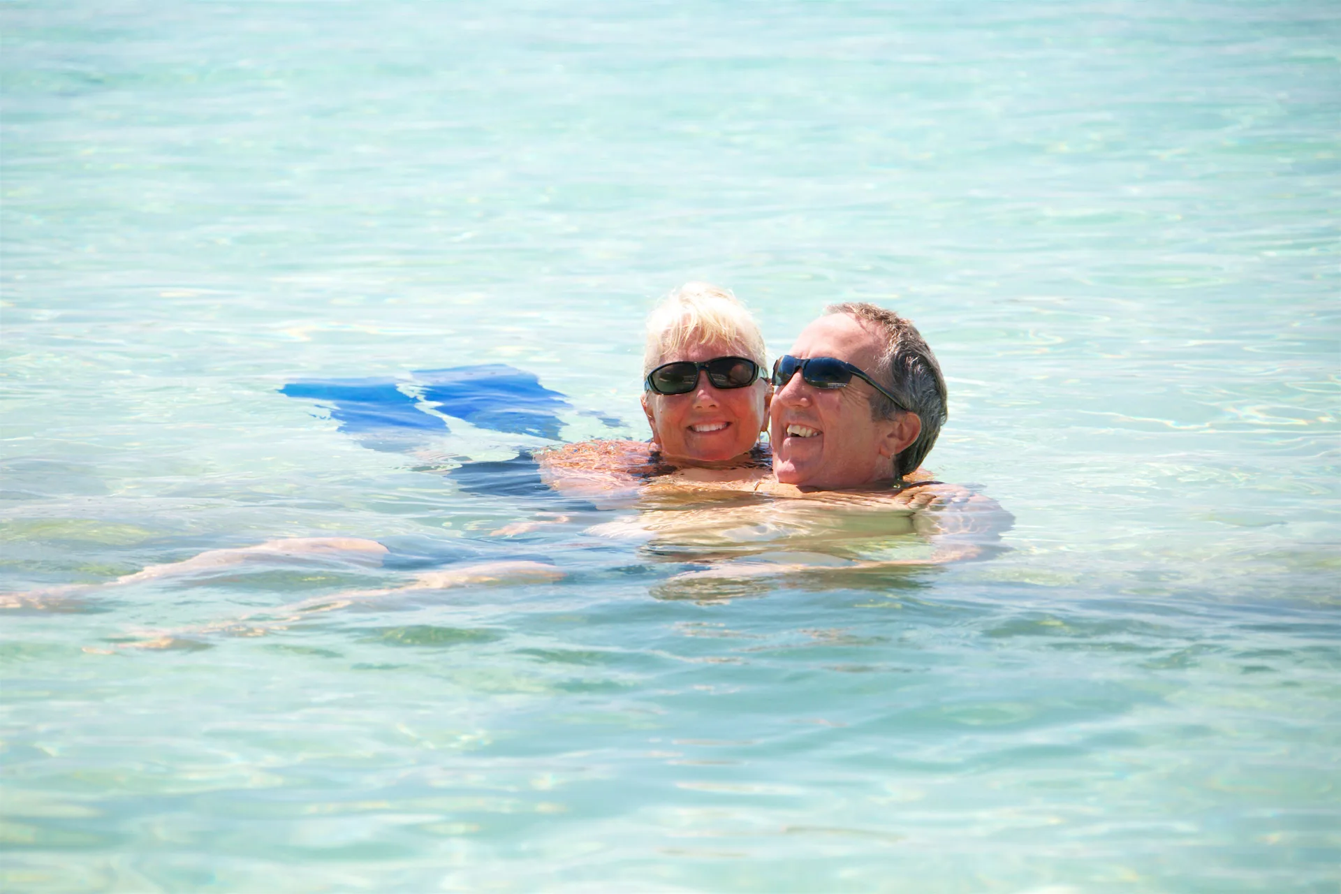 Two adults swimming in clear turquoise water at Secret Harbour Beach Resort.