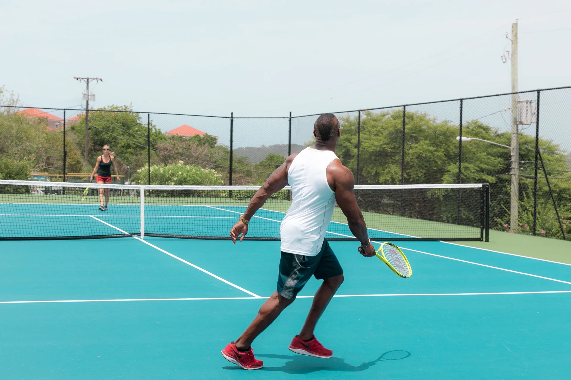 Two guests play tennis on a blue court at Secret Harbour Beach Resort.