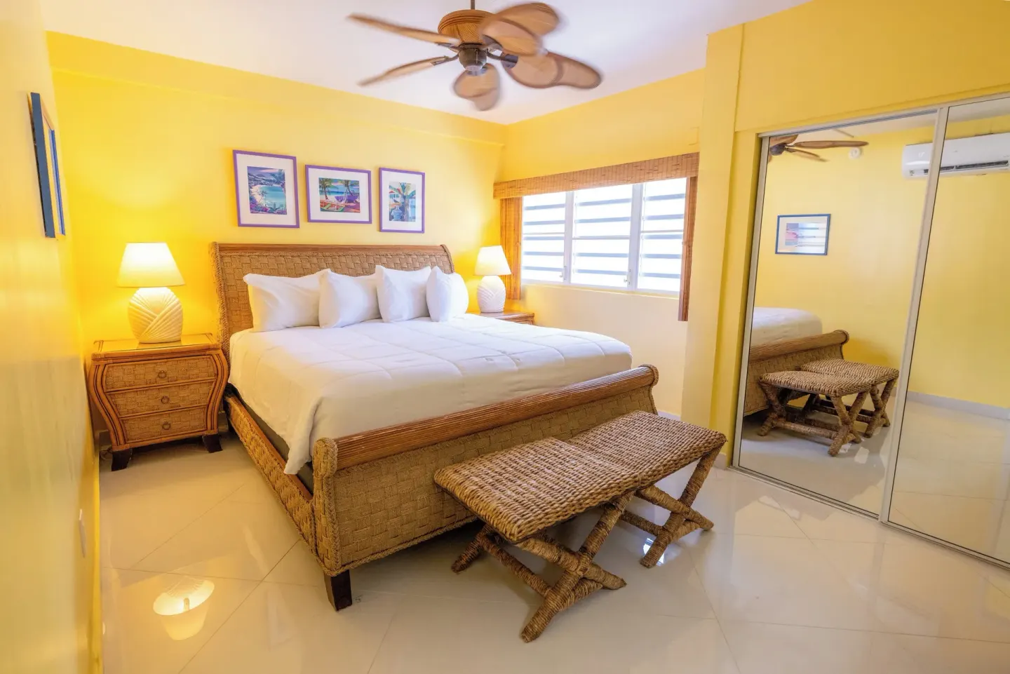 Yellow bedroom with wicker king bed and mirrored closet at Secret Harbour Beach Resort.