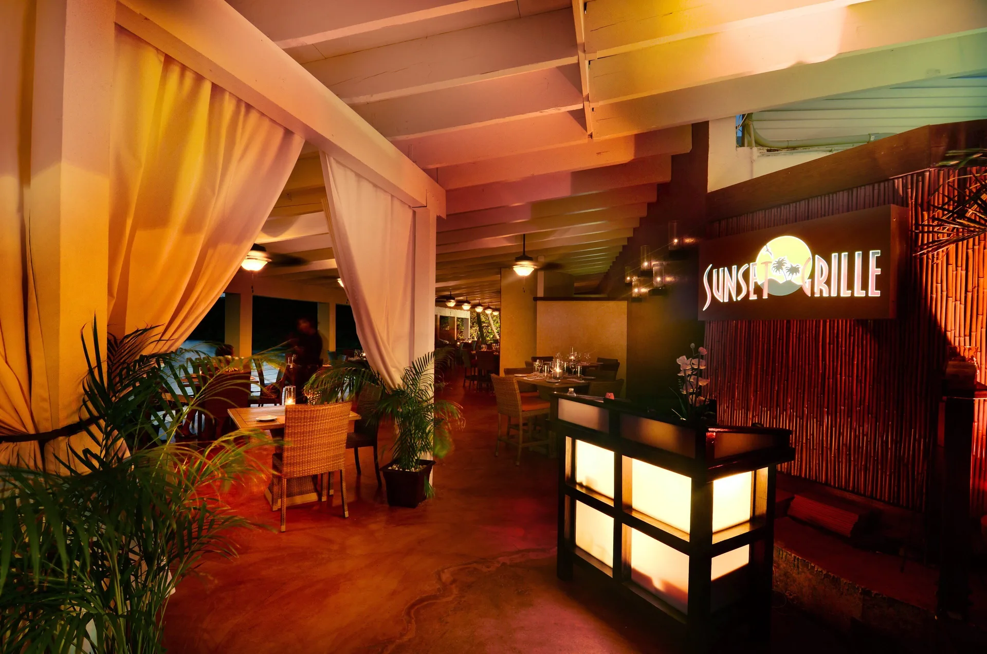Sunset Grille entrance sign and warmly lit dining area at Secret Harbour Beach Resort.