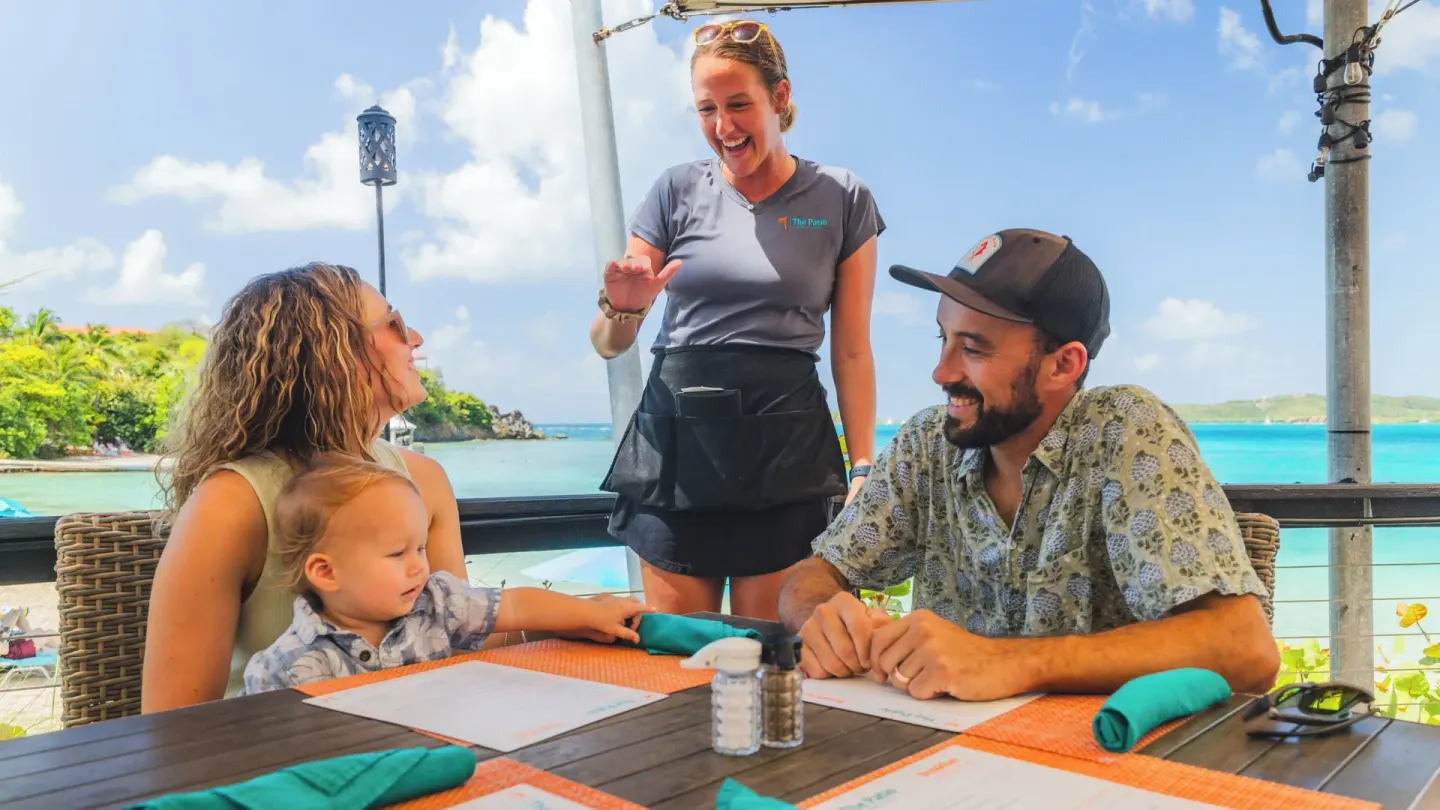 Server greeting a family at an outdoor table at Secret Harbour Beach Resort.