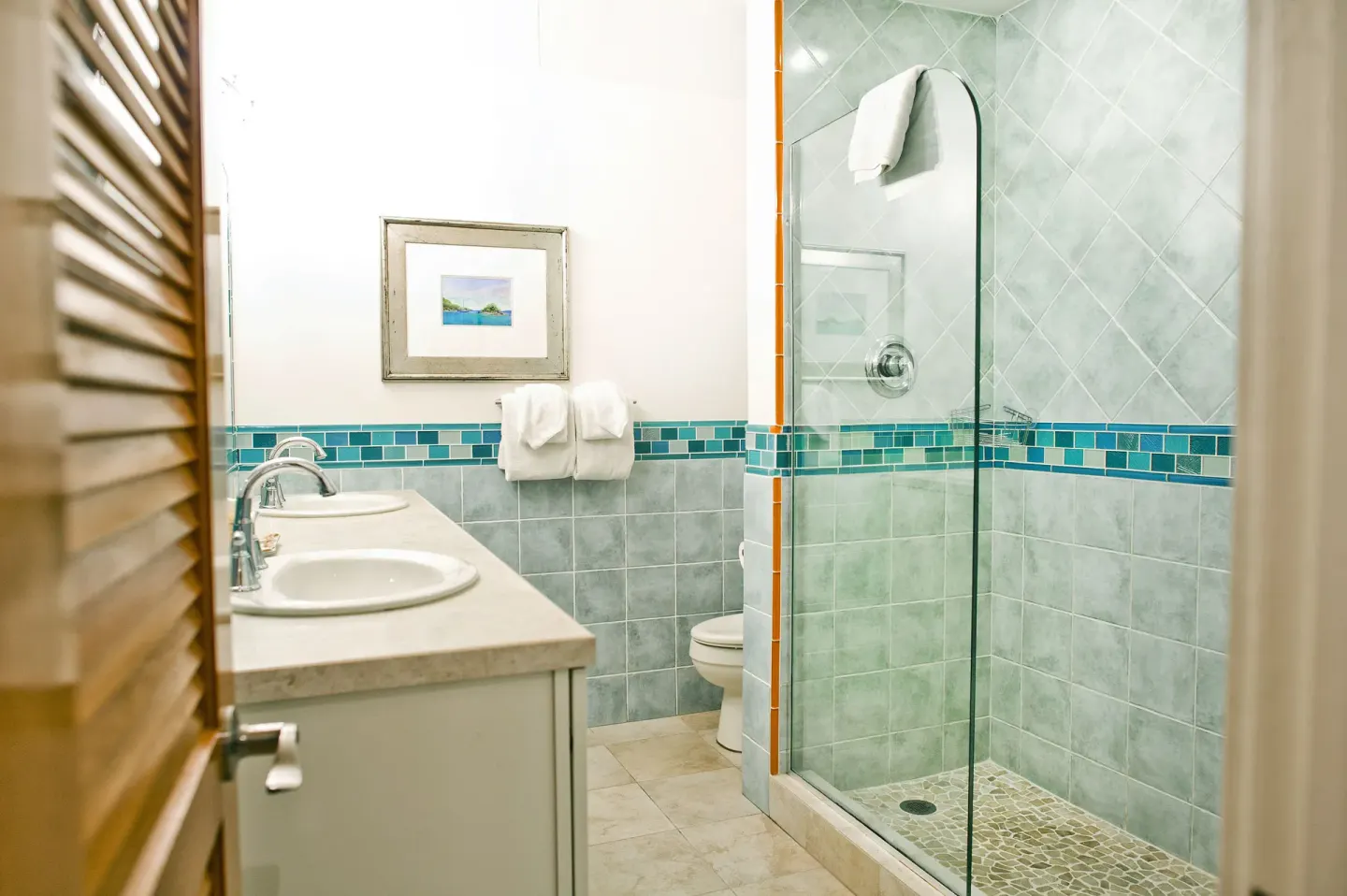 Beachfront condo bathroom with double sinks and glass shower at Secret Harbour Beach Resort.
