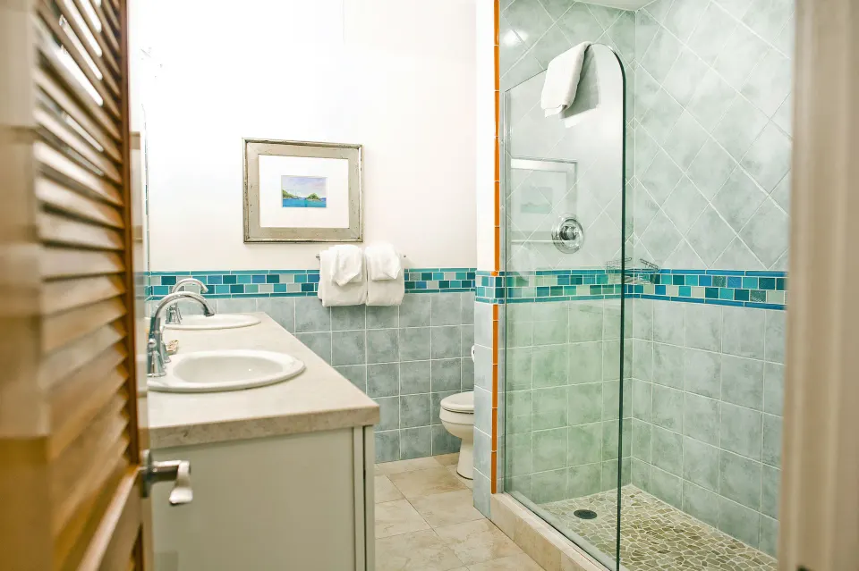 Beachfront condo bathroom with double sinks and glass shower at Secret Harbour Beach Resort.