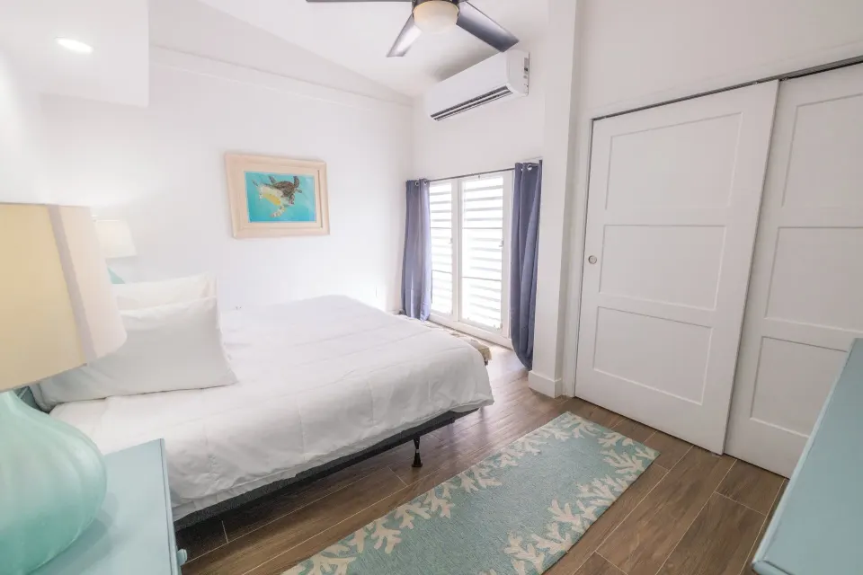 Bedroom with white bedding in a hillside one bedroom condo at Secret Harbour Beach Resort.
