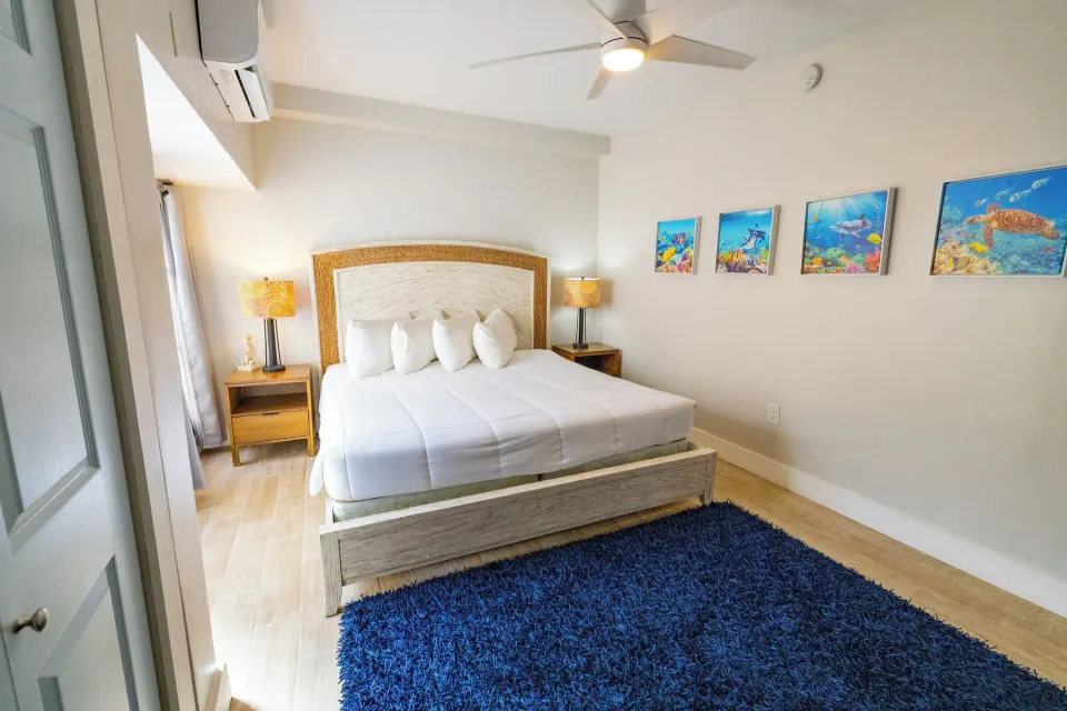 King bedroom with blue rug and ocean artwork at Secret Harbour Beach Resort.