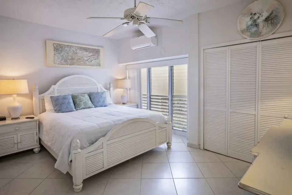 Queen bedroom with louvered closet doors in a hillside condo at Secret Harbour Beach Resort.