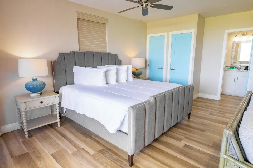 Studio Suite king bed beside blue doors and vanity area at Secret Harbour Beach Resort.