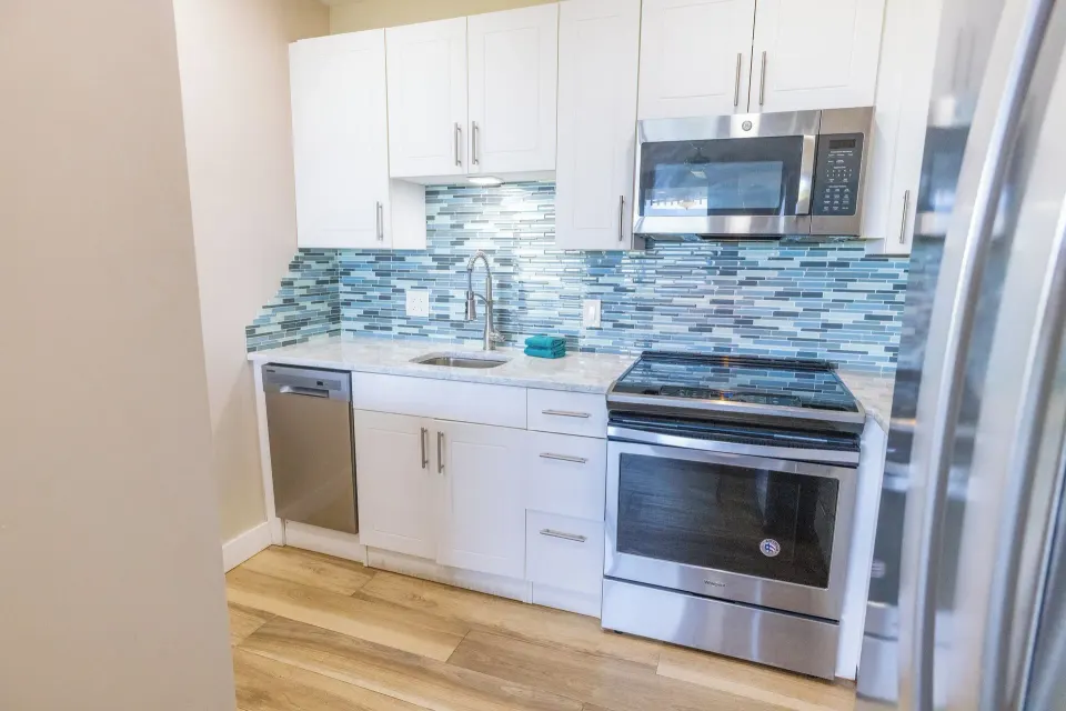 Studio Suite kitchen with white cabinets and stainless appliances at Secret Harbour Beach Resort.