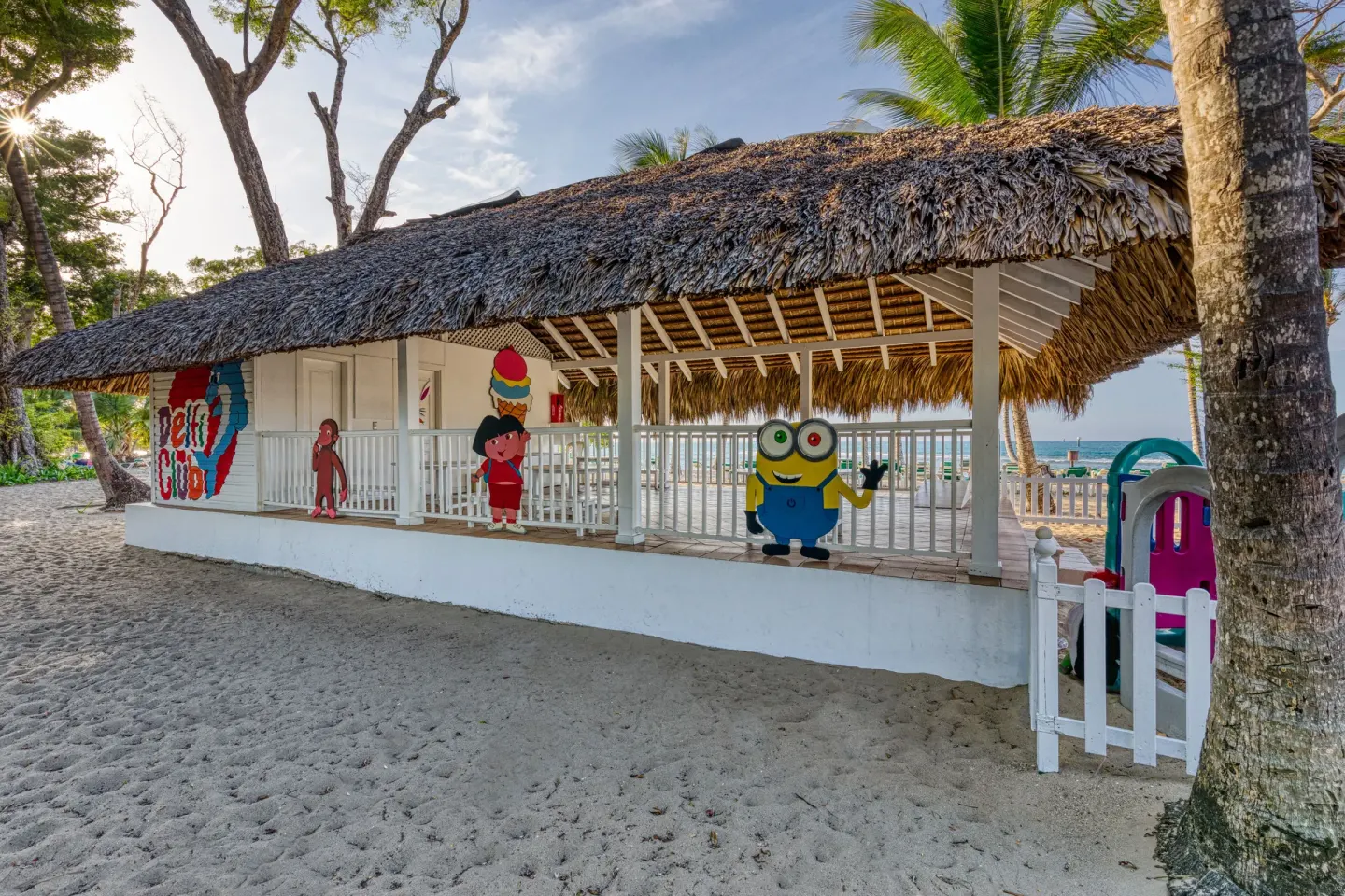 Thatched kids club building on the sand with cartoon murals at Senator Puerto Plata.