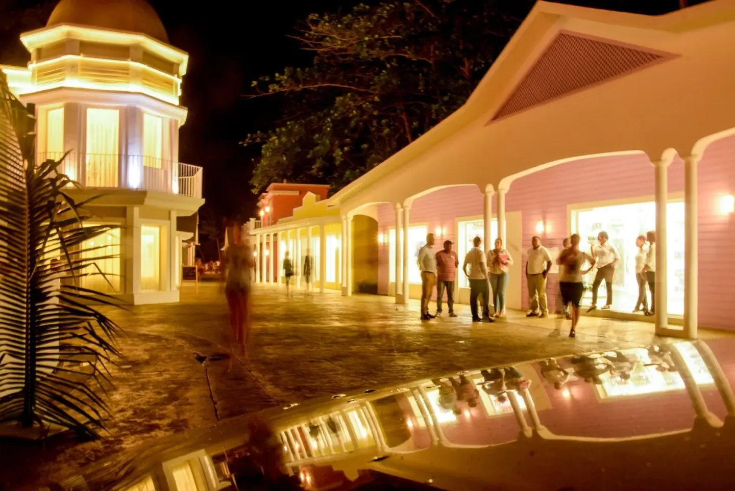 Evening promenade at Senator Puerto Plata with lit storefronts and guests walking outside.