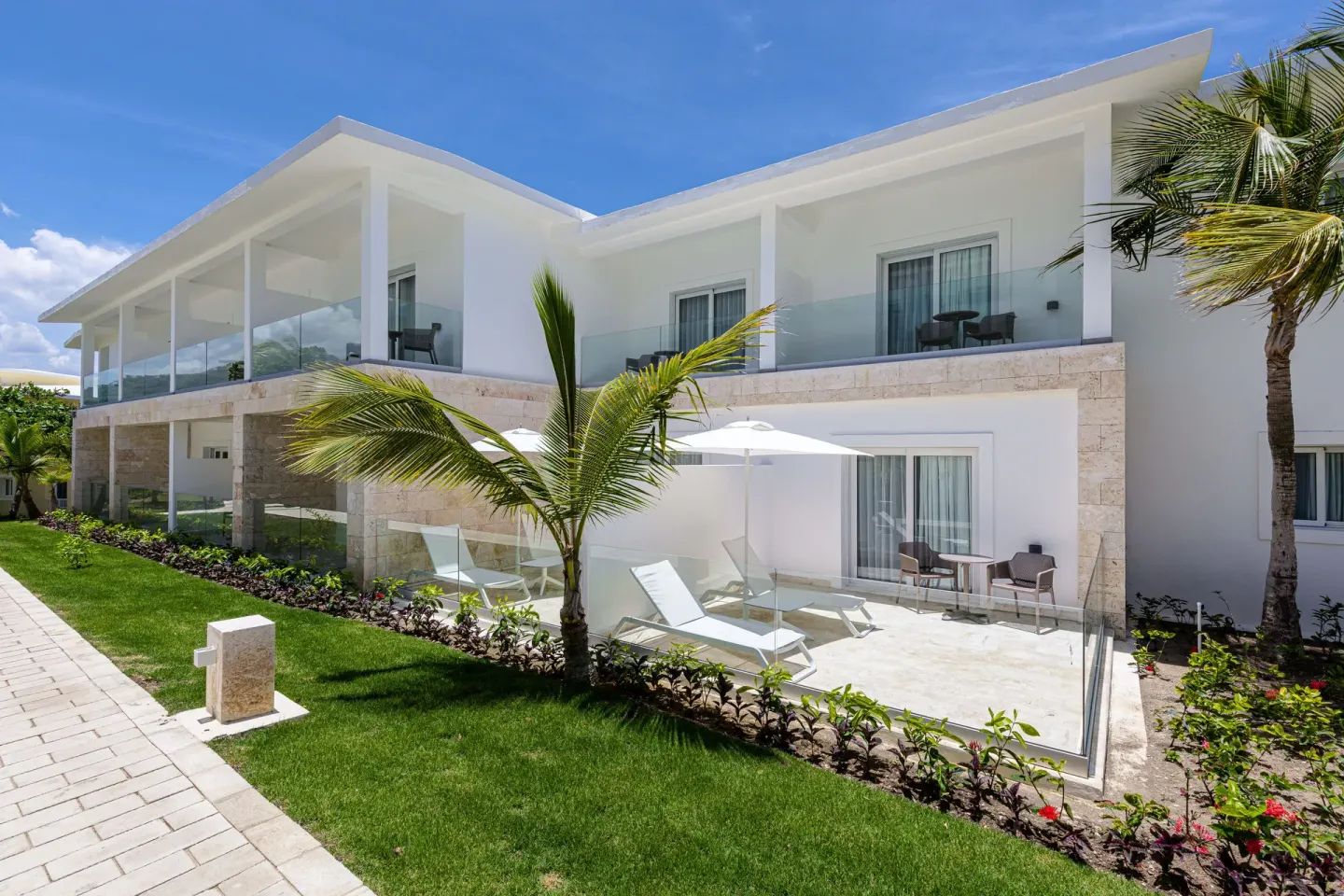 Guest building at Senator Puerto Plata with glass balconies, patios, palms, and lawn.
