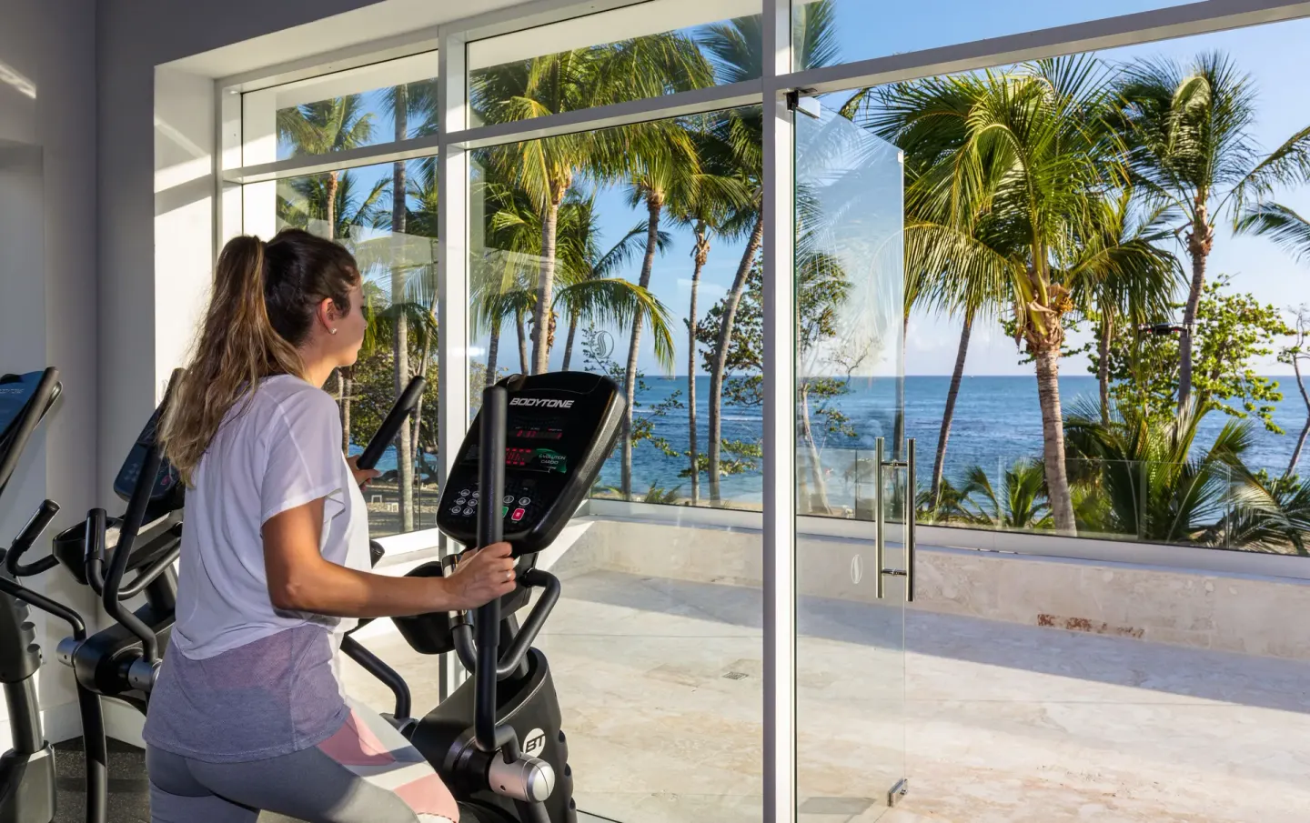 Guest using an elliptical in the ocean-view fitness room at Senator Puerto Plata.