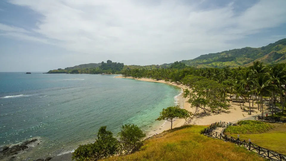 Curving palm-lined beach and blue bay beside Senator Puerto Plata.