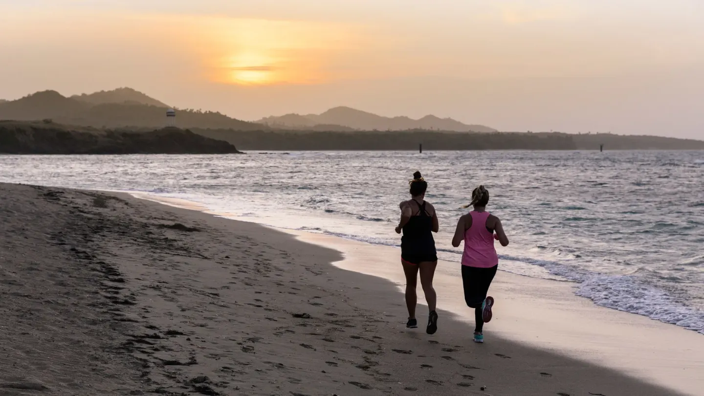 Two runners jogging along the beach at sunset near Senator Puerto Plata.