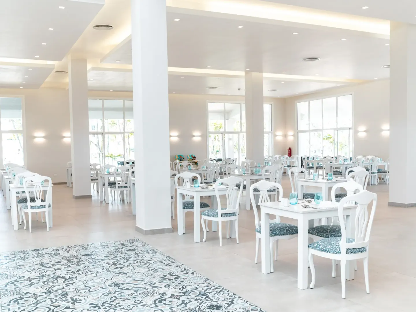 A white dining room with set tables and patterned tile at Senator Puerto Plata.