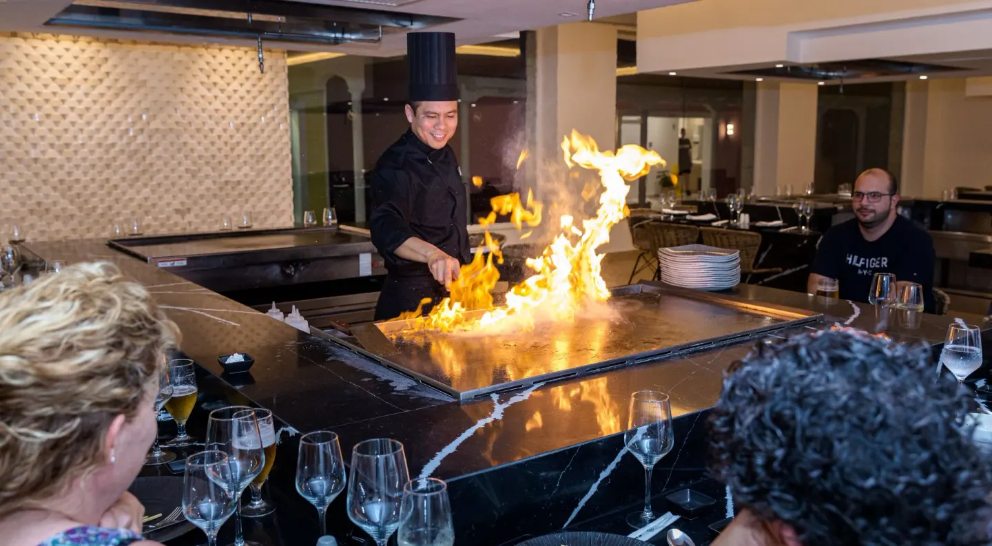 A chef cooks with flames on a teppanyaki grill at Senator Puerto Plata.