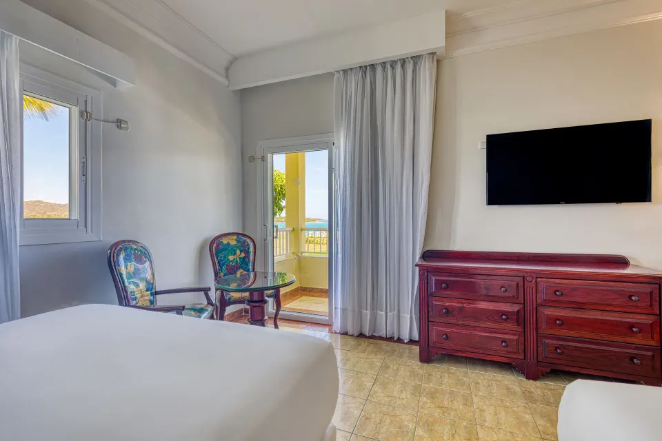 Junior Suite Ocean View room at Senator Puerto Plata with bed, balcony doors, TV and dresser.