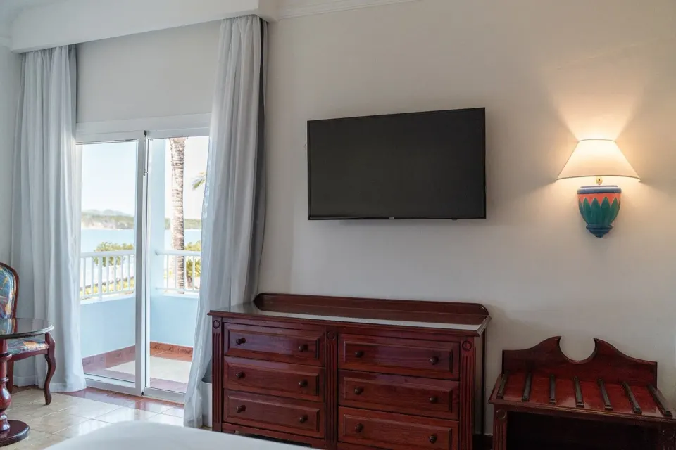 Junior Suite Ocean View at Senator Puerto Plata with balcony doors, TV, dresser and wall lamp.