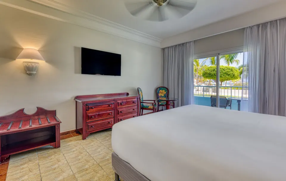 Senator Puerto Plata junior suite with bed, dresser, TV, and balcony doors.