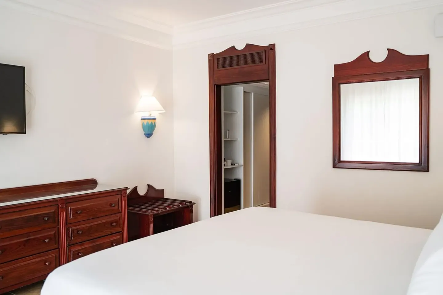 Senator Puerto Plata junior suite with bed, dresser, TV, mirror, and open closet area.
