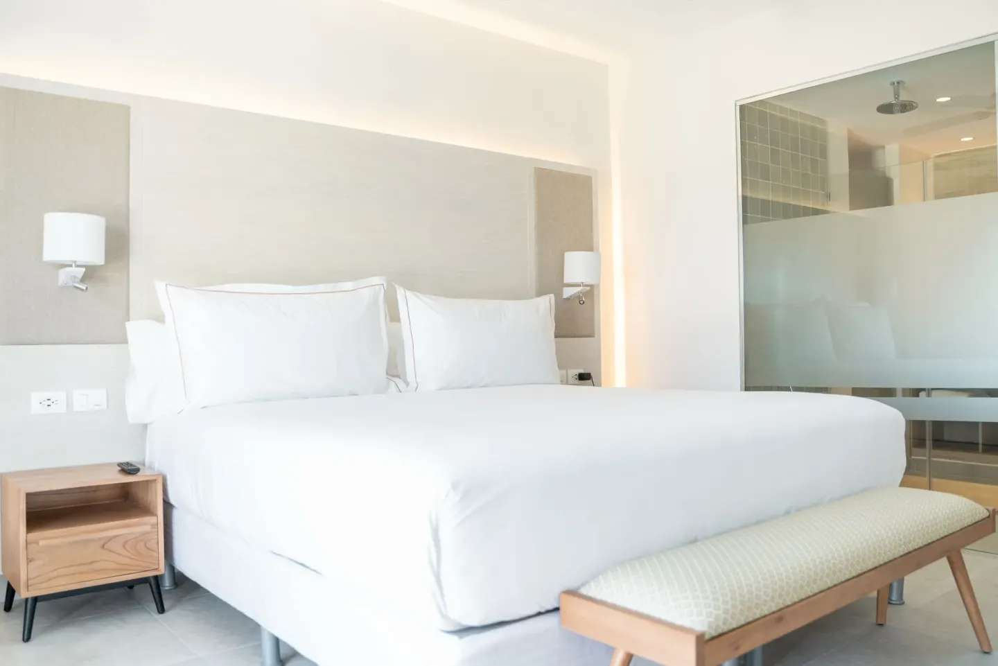 Luxury Junior Suite Ocean View bed with glass-walled shower at Senator Puerto Plata.