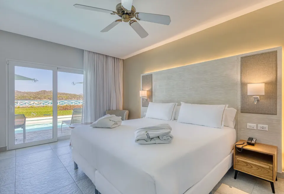 King bed in a swim-up ocean view suite at Senator Puerto Plata with terrace beyond.
