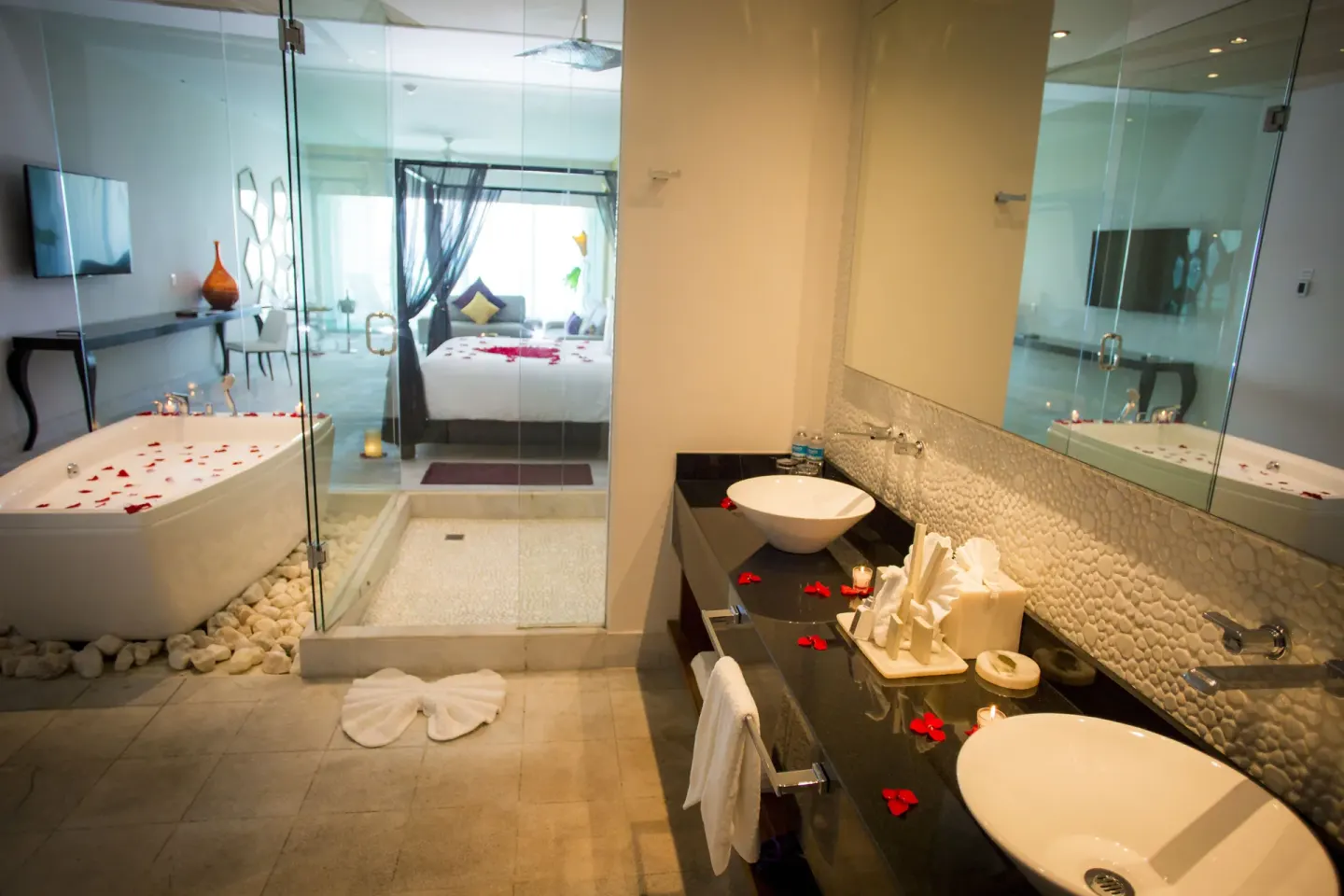 Bathroom vanity, tub, and bedroom beyond at Senses Riviera Maya Oceanfront.