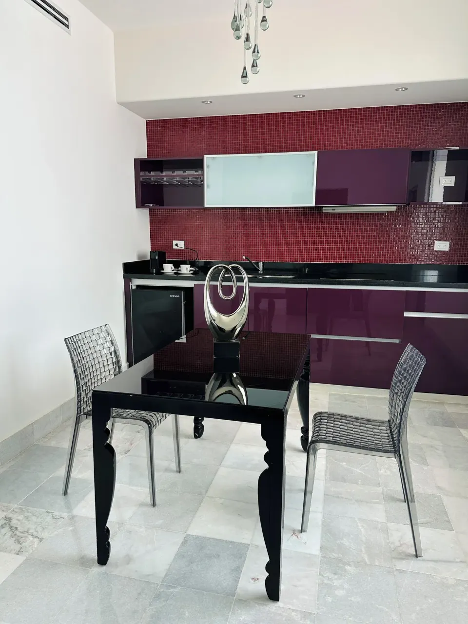 Guest room dining area with kitchenette and chandelier at Senses Riviera Maya Oceanfront.