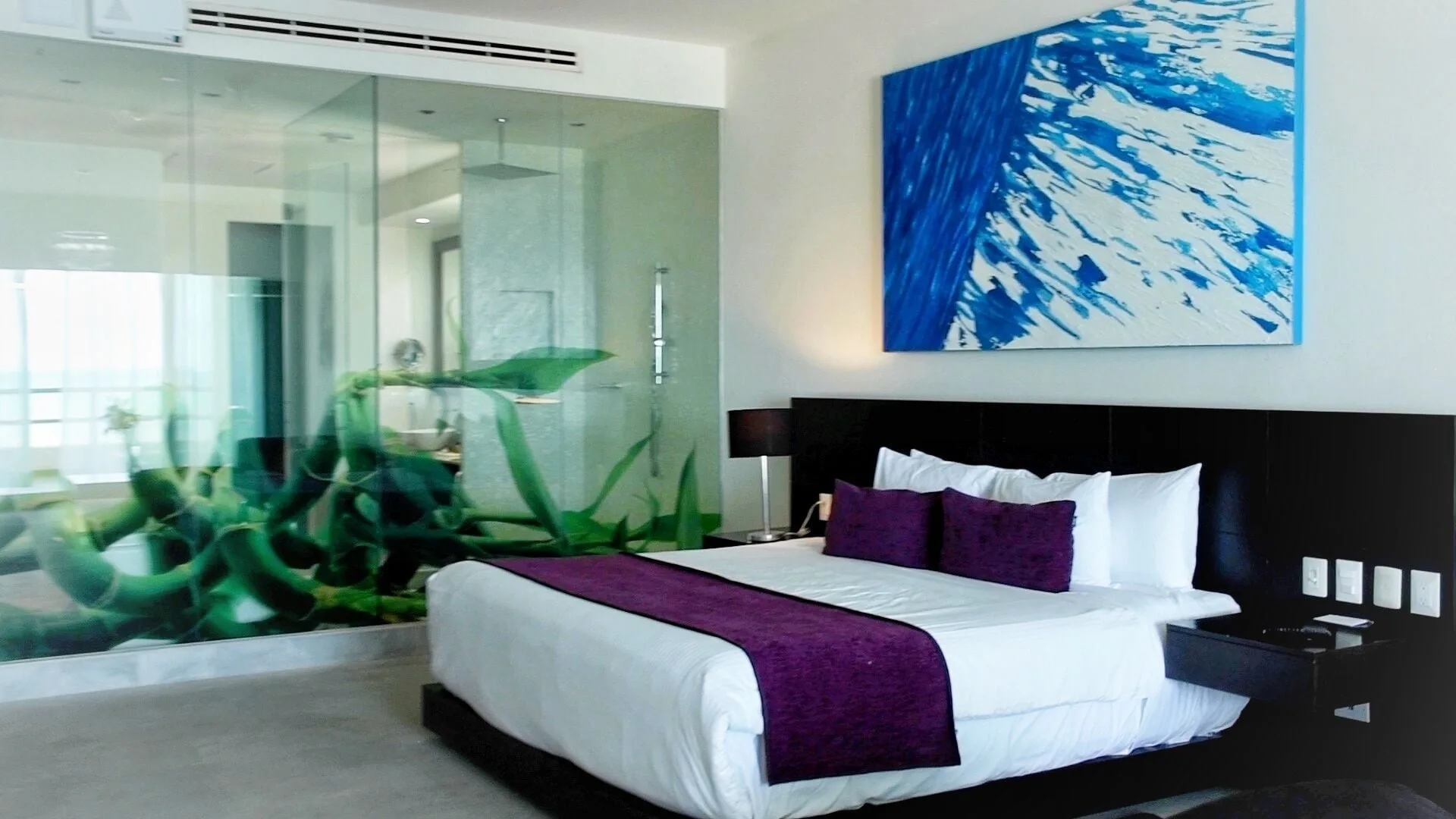 Guest room king bed beside glass bath artwork at Senses Riviera Maya Oceanfront.