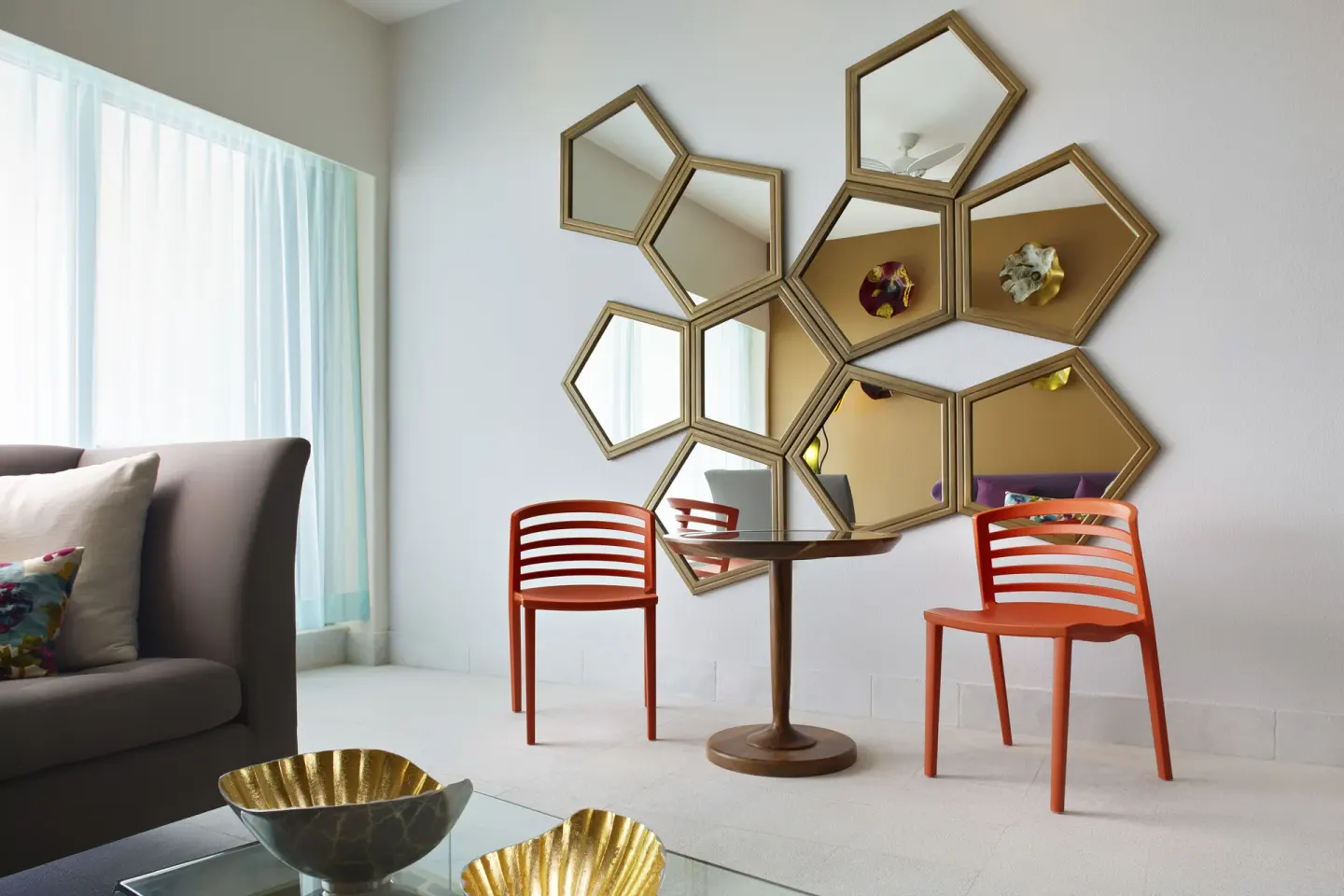 Seating area with orange chairs and geometric mirrors at Senses Riviera Maya Oceanfront.