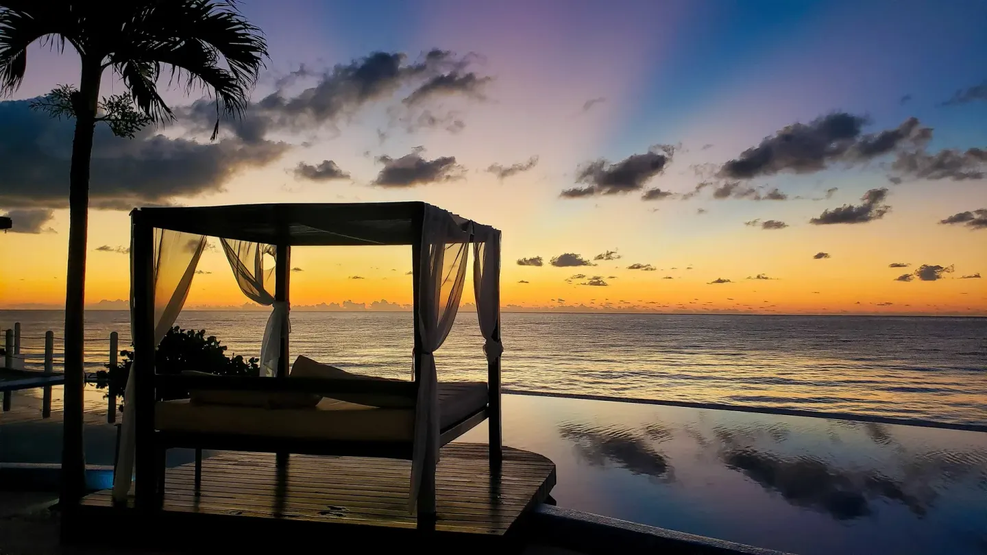 Canopied daybed by the infinity pool at sunrise at Senses Riviera Maya Oceanfront.