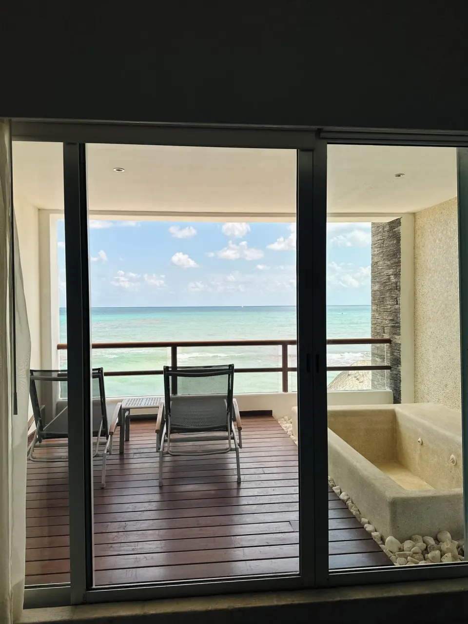 Sliding doors open to a balcony with lounge chairs at Senses Riviera Maya Oceanfront.
