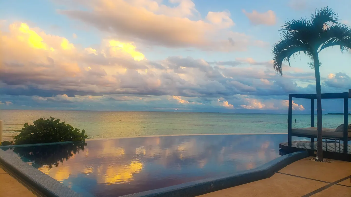 Infinity pool reflecting sunset clouds beside the ocean at Senses Riviera Maya Oceanfront.
