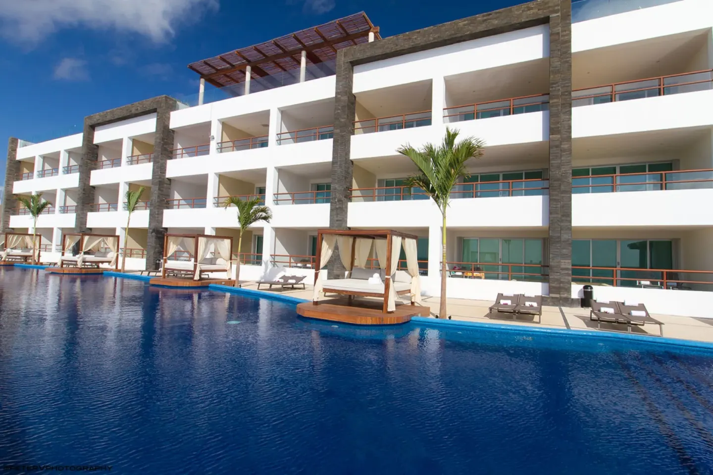 A white guestroom building overlooks the pool at Senses Riviera Maya Oceanfront.