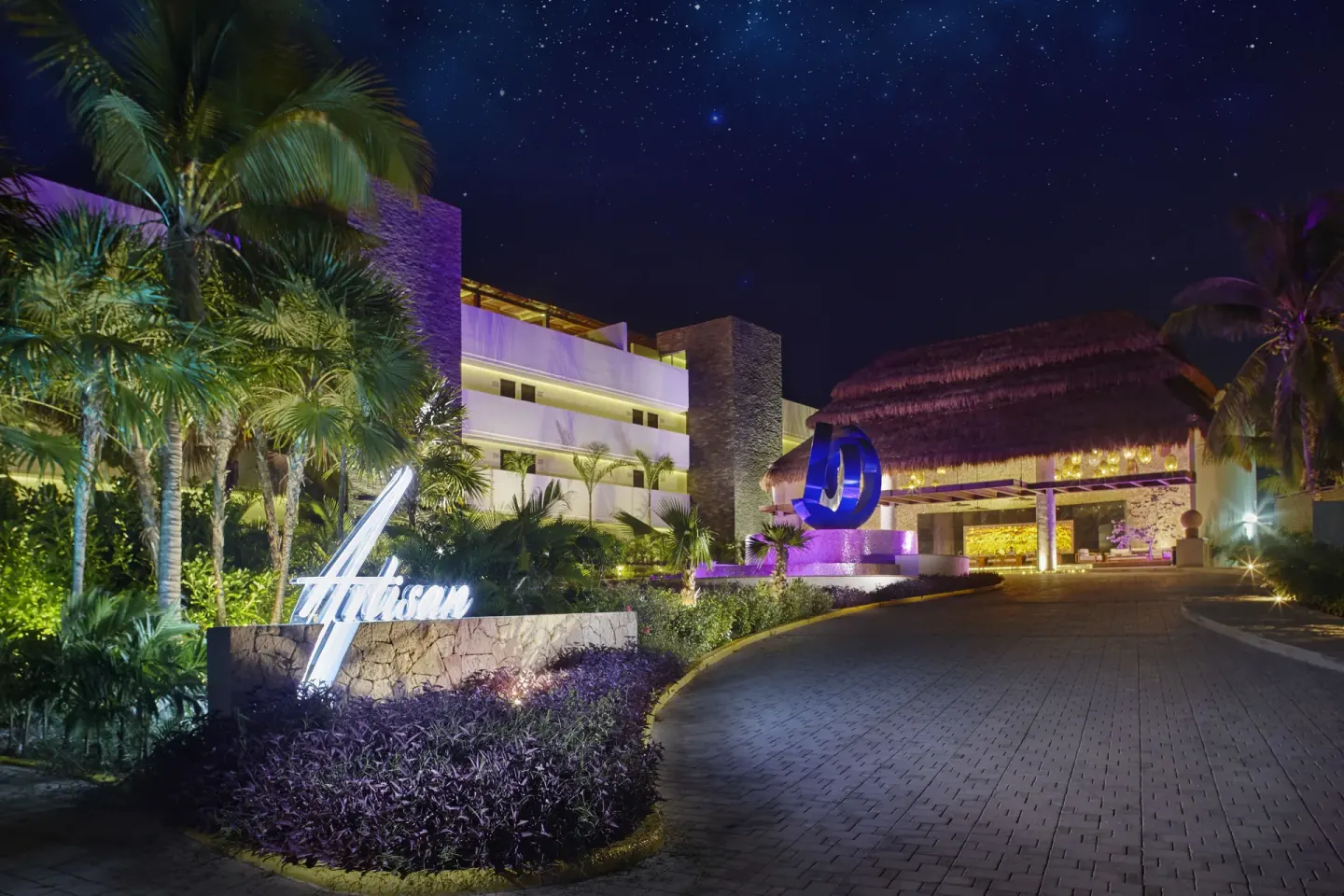 The illuminated resort entrance and driveway at night at Senses Riviera Maya Oceanfront.