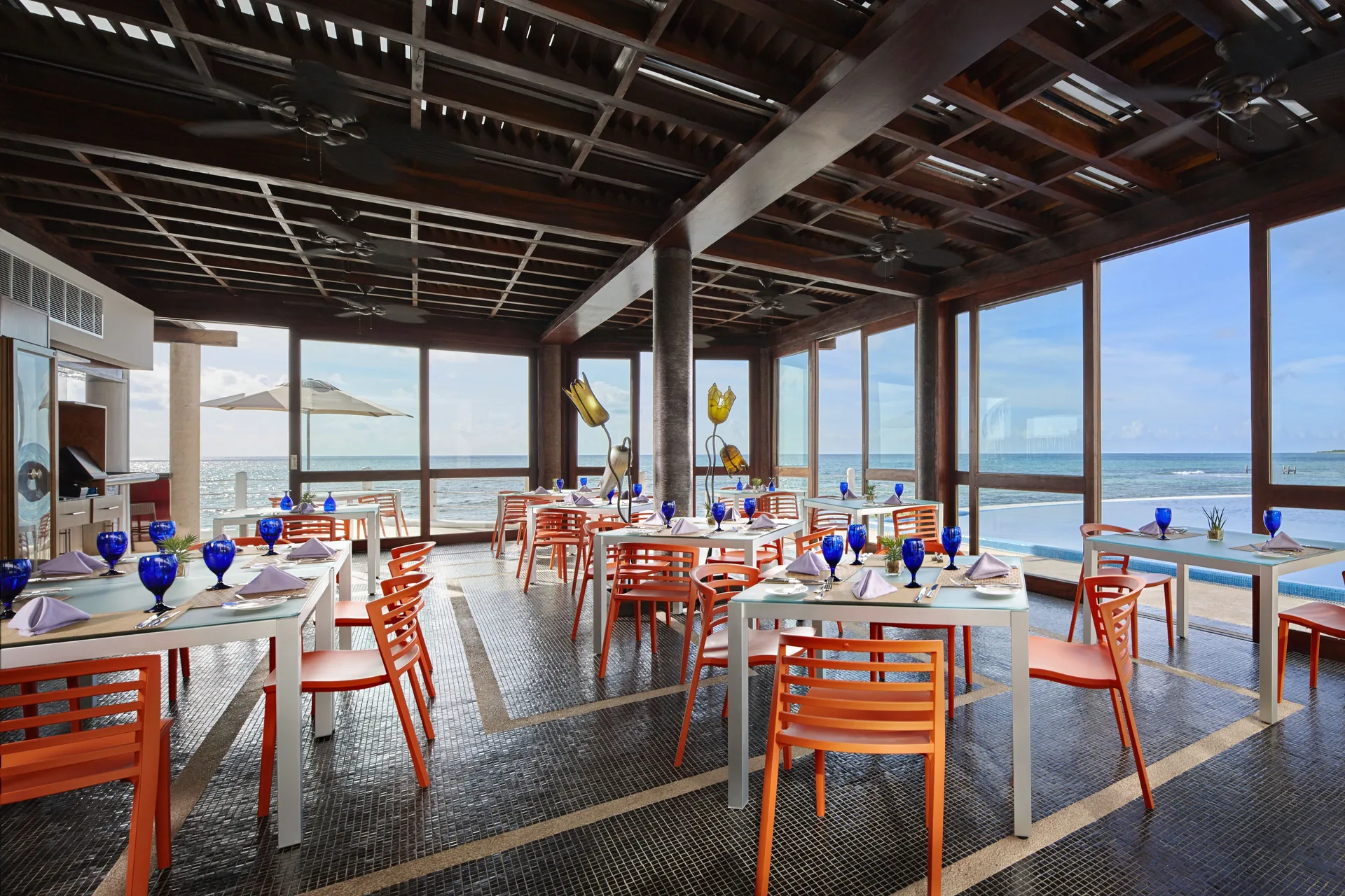 An ocean-view dining room with orange chairs at Senses Riviera Maya Oceanfront.