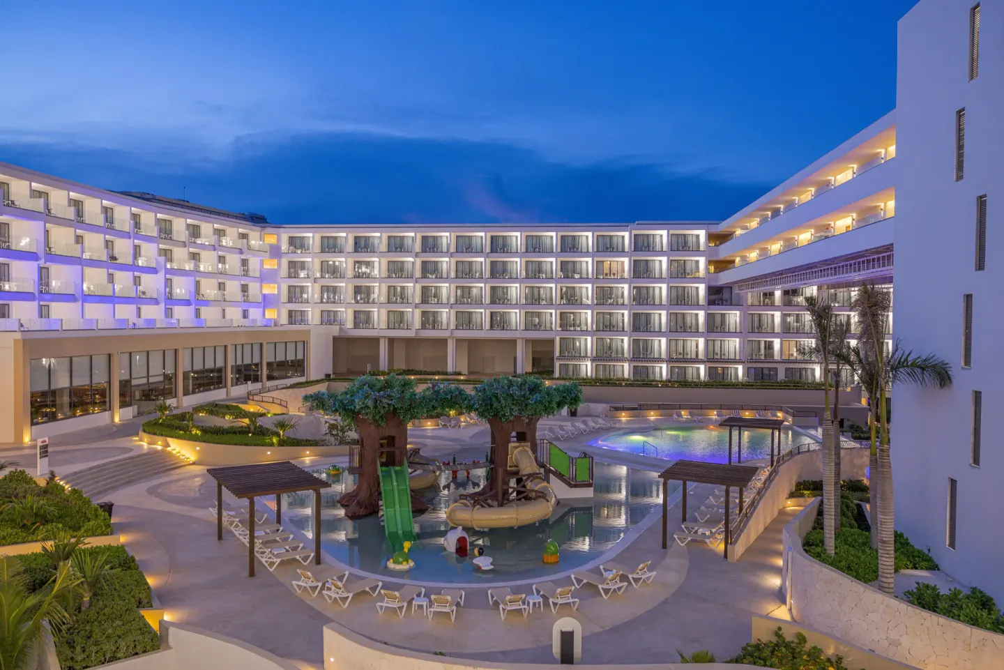 Evening view of the resort pool and water play area at Sensira Resort & Spa Riviera Maya.